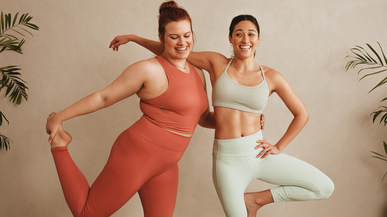 Two friends doing yoga together in workout attire