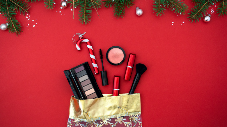 Christmas flat lay with makeup products in gift bag on red background