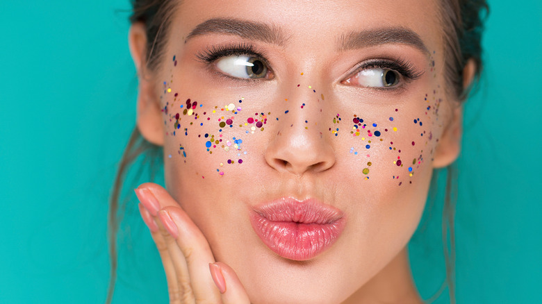 Woman with glitter lip gloss and glitter on face