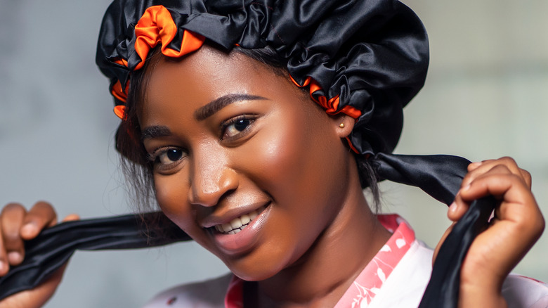 Woman tying hair bonnet in place