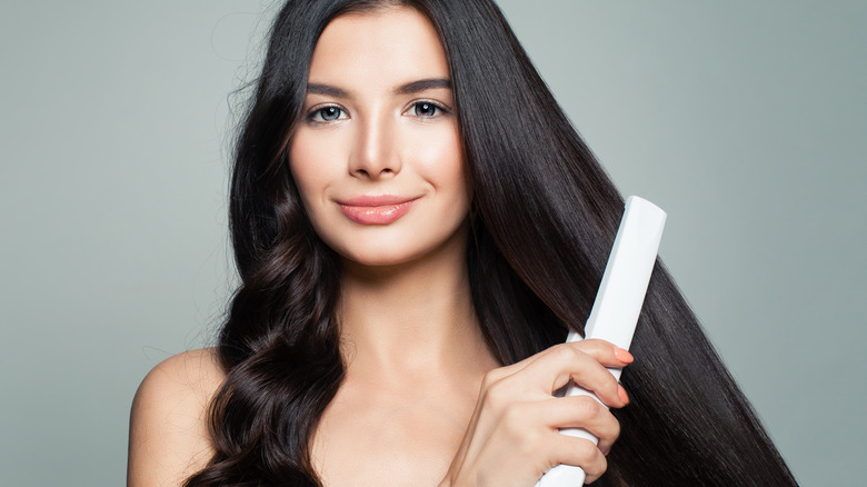 Young woman straightening hair