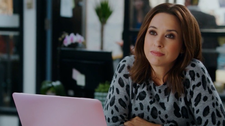 Lacey Chabert sitting at a laptop in "Crossword Mysteries: Riddle Me Dead"
