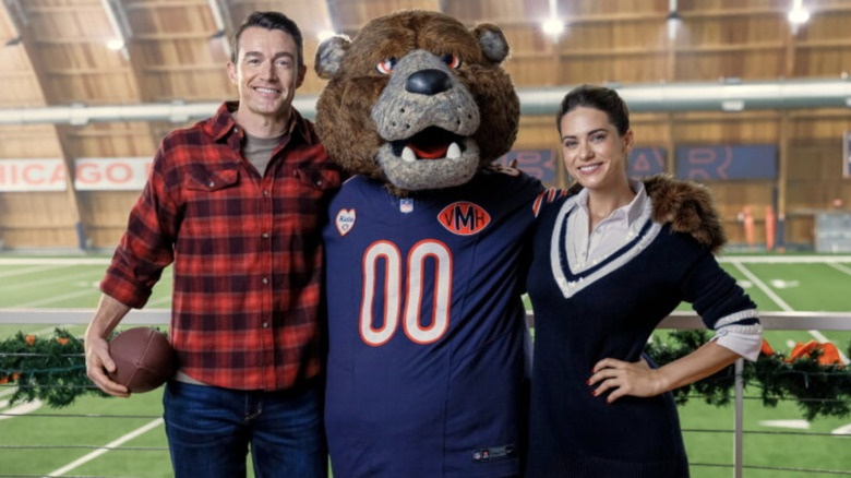 Robert Buckley and Lyndsy Fonseca posing with mascot for Holiday Touchdown: A Bears Love Story