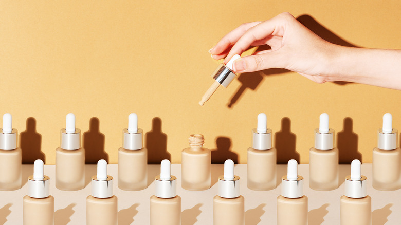 Woman pulling applicator out of foundation bottle