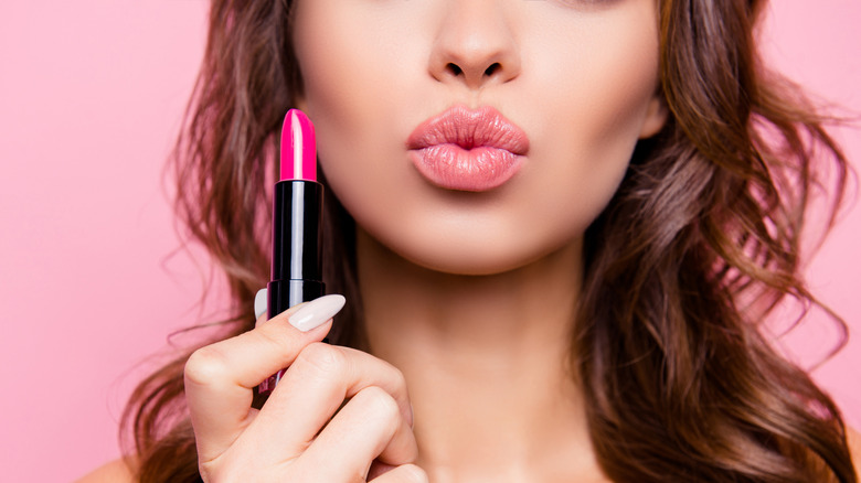 Woman holding up a pink lipstick