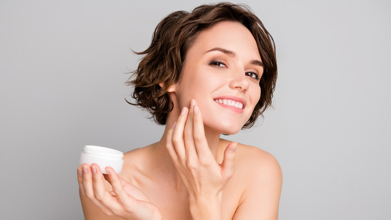 A woman applying face cream 