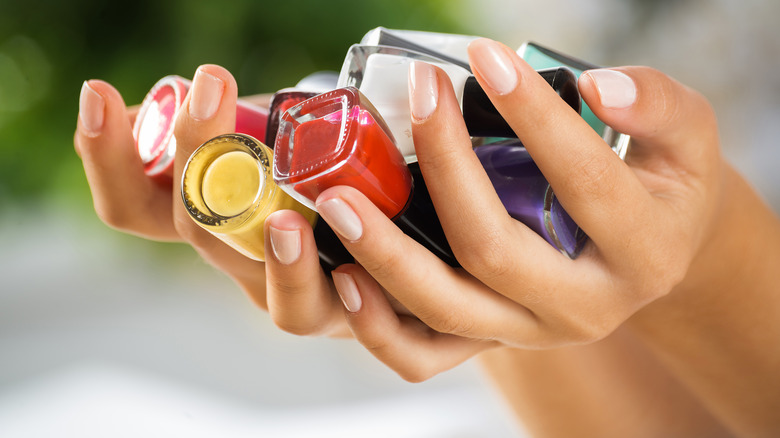 Person holding a handful of nail polishes
