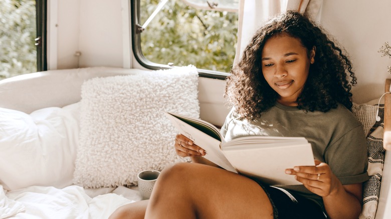 Black woman reading book in camper van