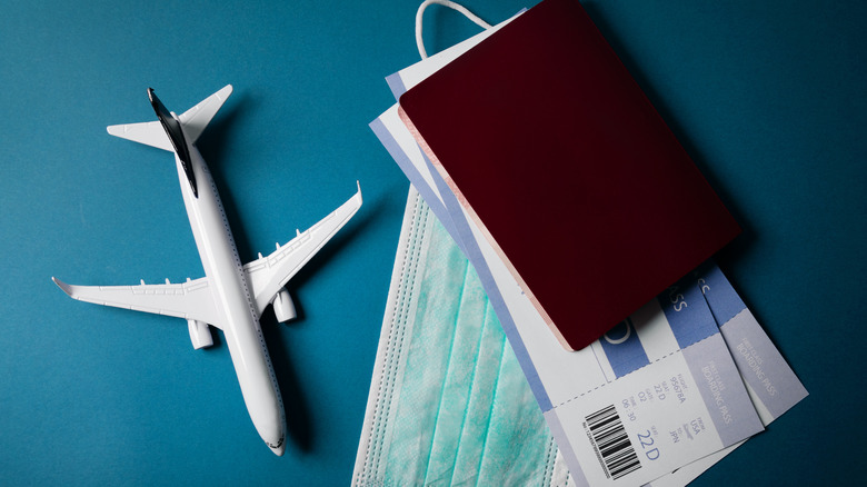 Mask and plane tickets next to toy plane