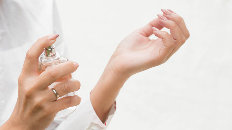 Woman spraying perfume onto wrist 