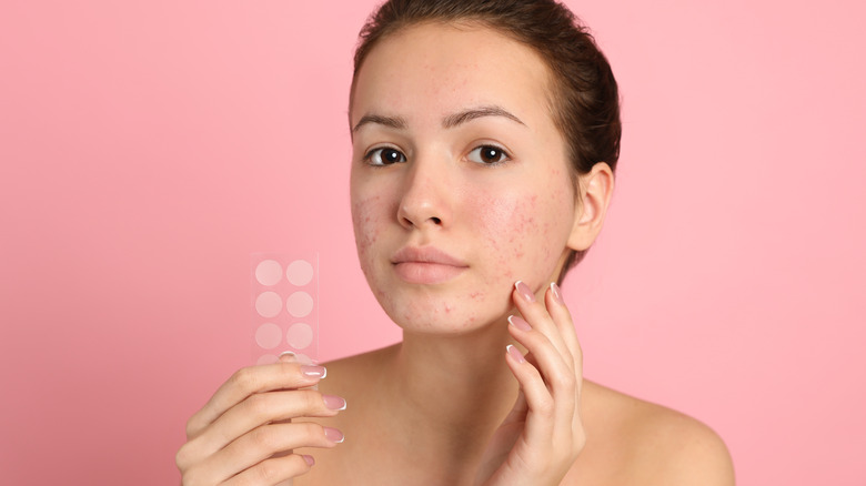 woman putting on a pimple patch