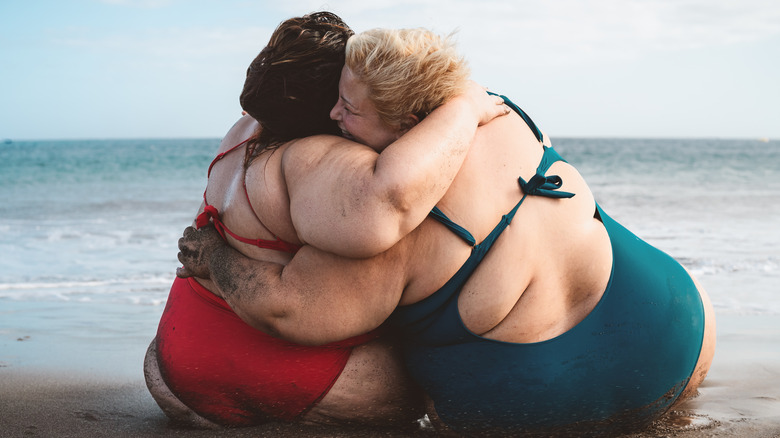 women hugging on the beach
