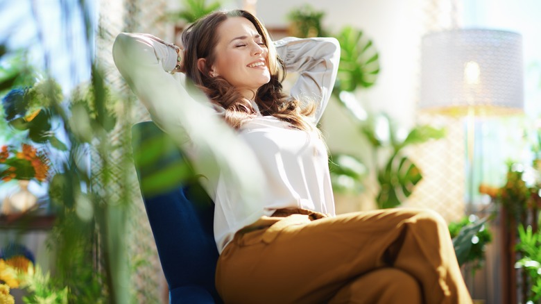 happy woman sitting on chair surrounded by plants