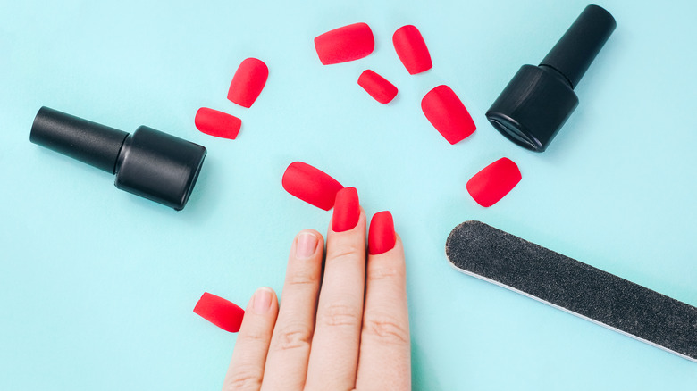 Red press on nails being applied 