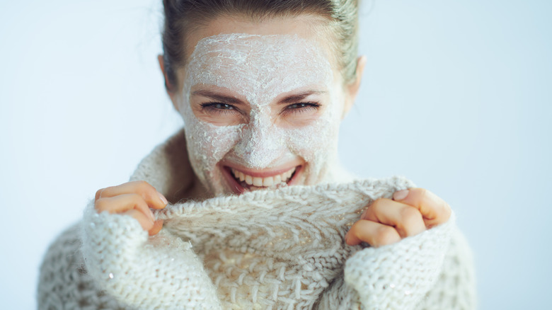 woman wearing knit sweater and clay face mask