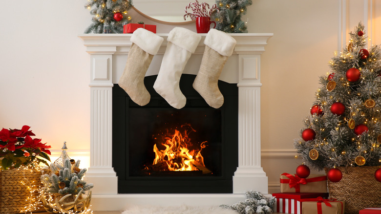 White stockings sitting on a fireplace next to a Christmas tree