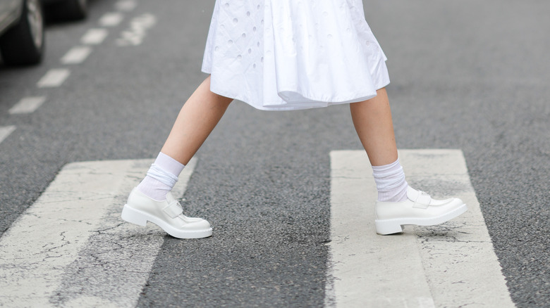 Gabriella Berdugo wearing white prada dress and white loafers while crossing the street in paris