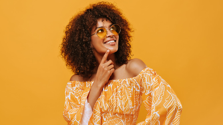 Woman with round sunglasses and yellow background