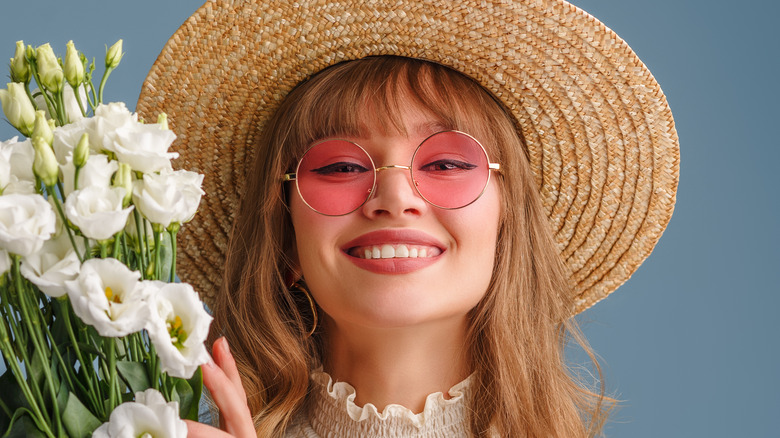 Woman with round pink sunglasses and a straw sunhat