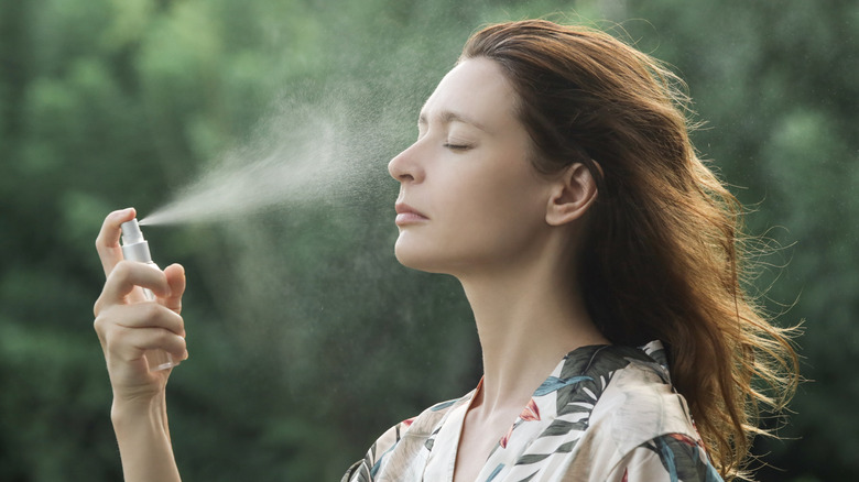 A woman using sunscreen spray 