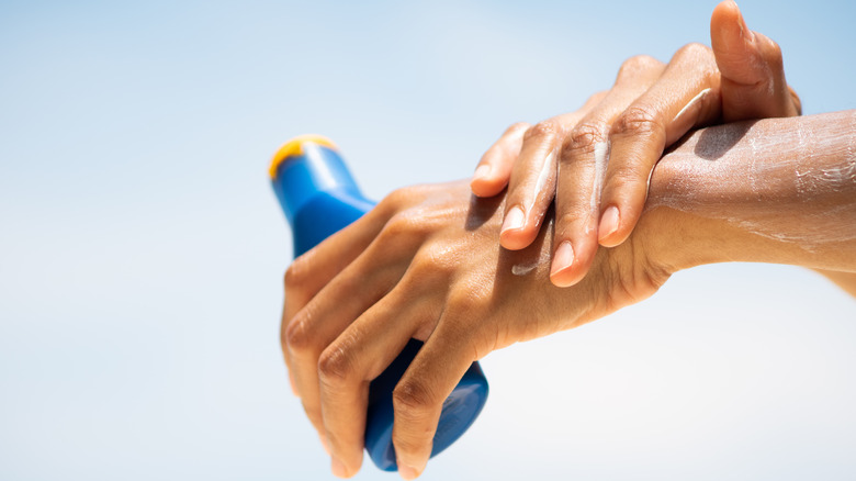 A woman applying sunscreen on her hands