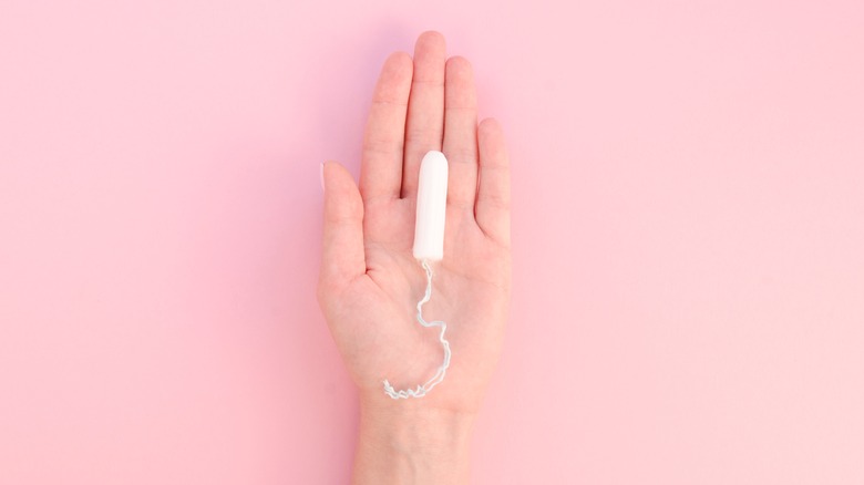 A hand holding a tampon