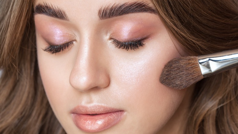 Woman applying highlighter makeup 