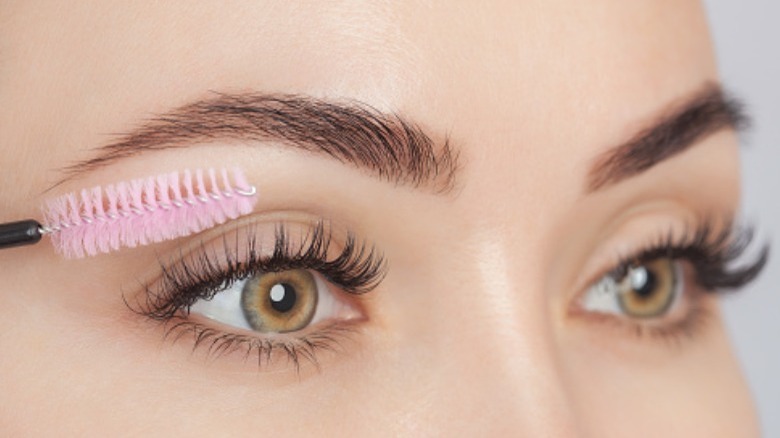 Woman uses spoolie on eyelashes