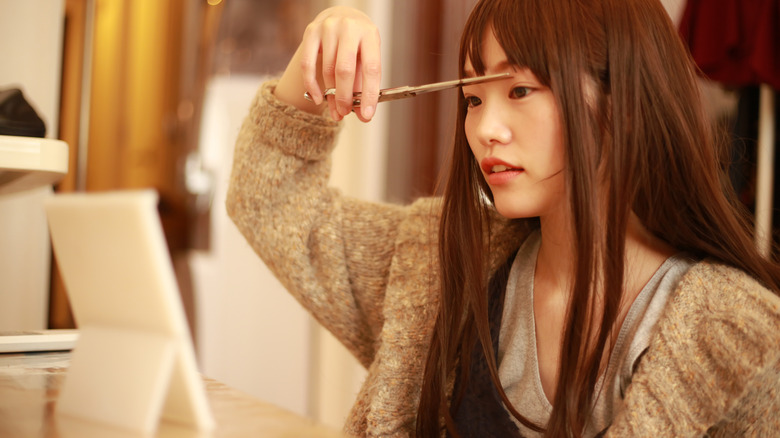 Woman cutting her own bangs