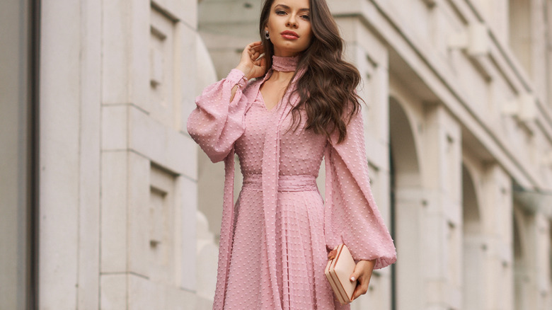 woman outside wearing pink dress and clutch bag