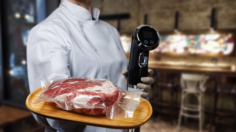Cook shows Packed meat on a wooden tray and Sous vide immersion circulator cooker