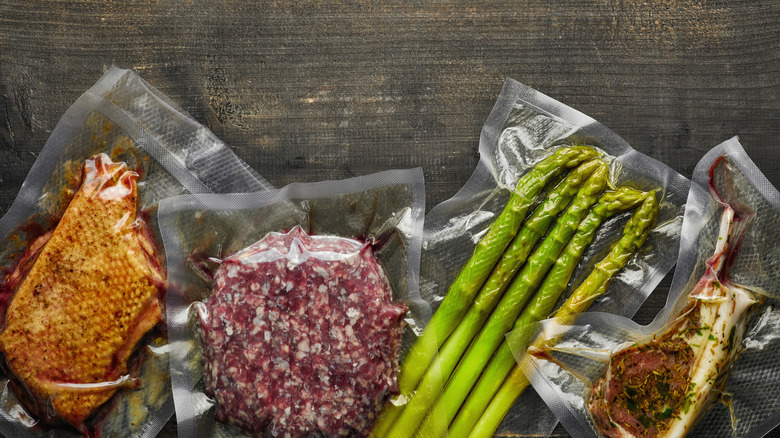 asparagus and red meats vacuum sealed ready for sous vide cooking on wooden table, from above