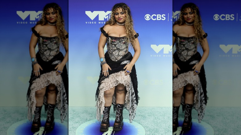 Bella Kay posing in an over-the-top, gothic-inspired dress and boots