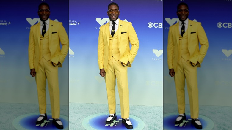 Kel Mitchell posing in a yellow suit with Pluto TV-branded accessories