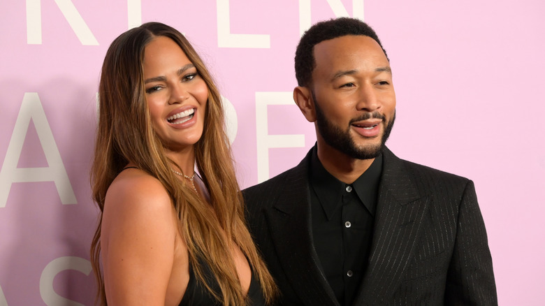 John Legend and Chrissy Teigen against pink background