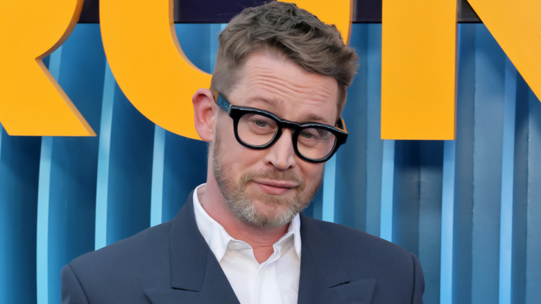 Macaulay Culkin smirking and tilting his head slightly downward