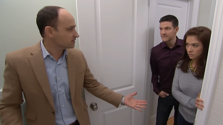 David Visentin gestures at an unhappy looking couple standing in a doorway on Love It or List It