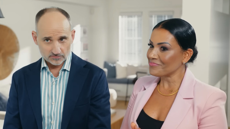 Page Turner stands smiling next to a serious David Visentin in a brightly lit room on Love It or List It