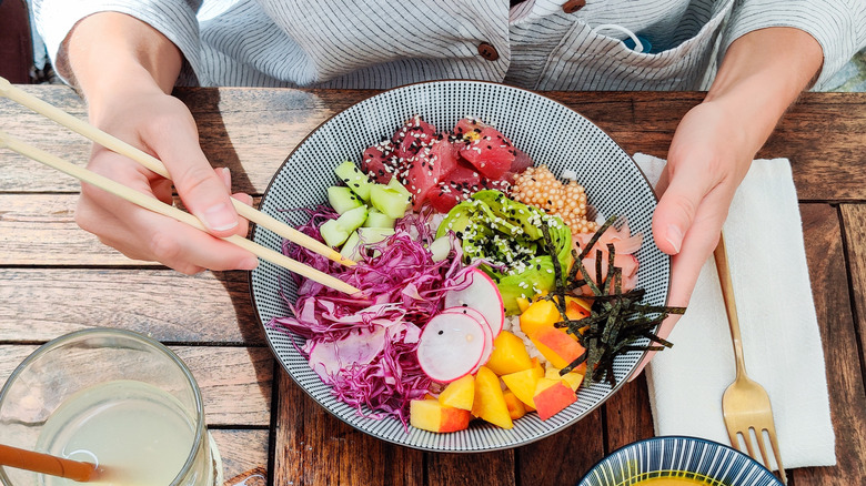 Hand with chopsticks grabbing food