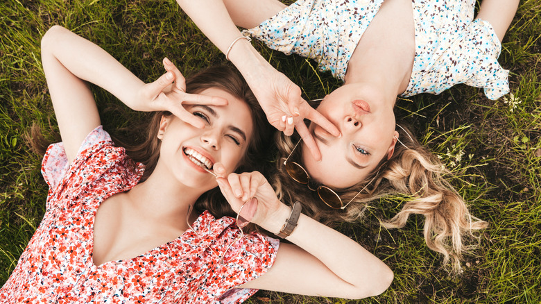 two young woman laying on the grass in summer dresses 