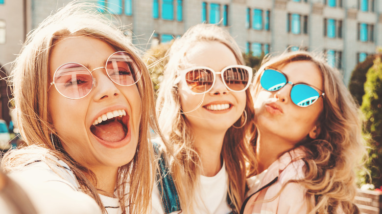 three young woman smiling with sunglasses in the summer 