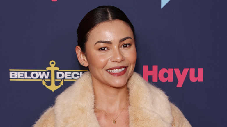 Dani Soares in cream fur coat with hair slicked back in a bun