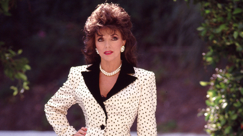Joan Collins poses in a Nolan Miller suit with a polka dot wide shouldered jacket on the set of the TV series Dynasty in Hollywood, California in June 1988.