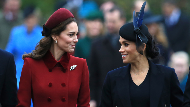 Kate Middleton and Meghan Markle looking at each other and talking