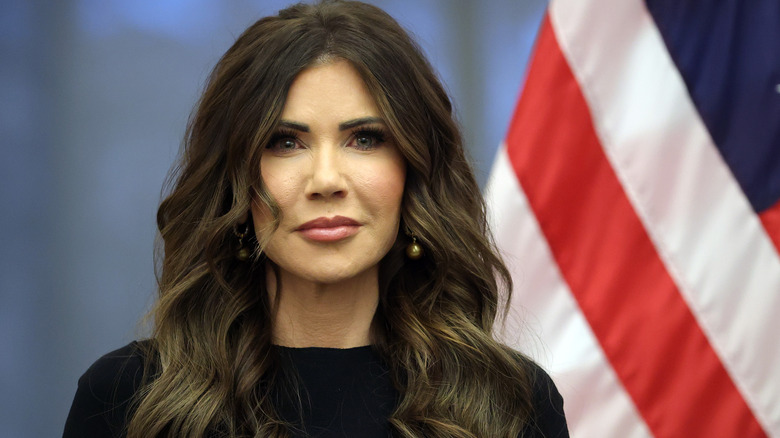 Kristi Noem wearing black in front of the American flag