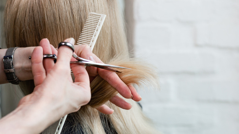Hairstylist cutting long blonde hair 