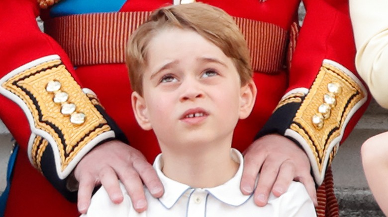 Prince George looks upwards while being held by his father