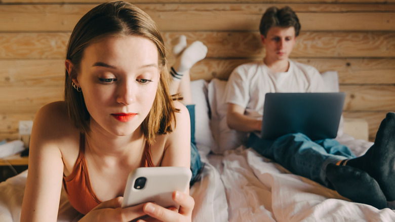couple in bed on electronics