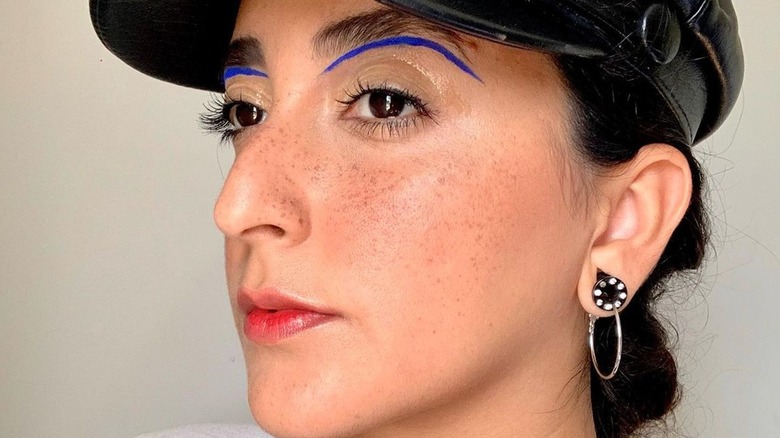 Woman with blue liner outlining bottom of brows