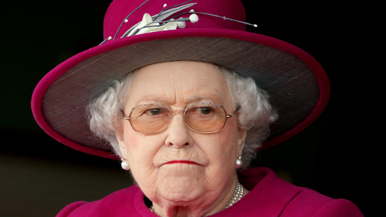 Queen Elizabeth red hat frowning